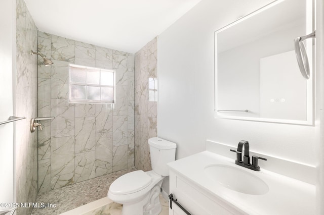 bathroom featuring toilet, vanity, and tiled shower