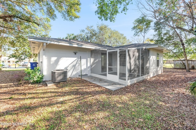 rear view of house featuring central AC unit and a sunroom