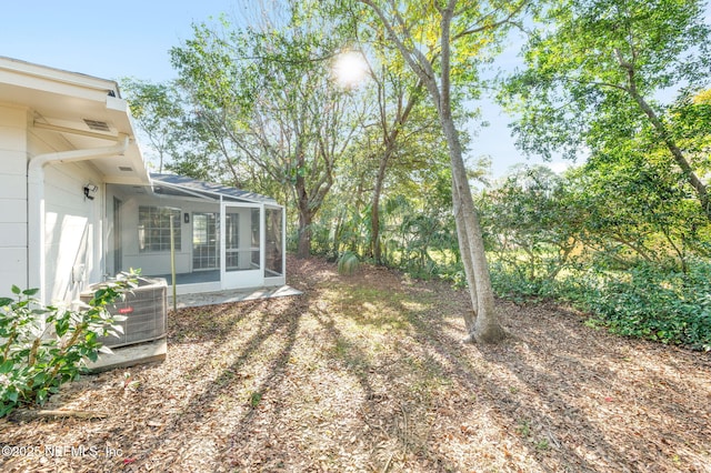 view of yard featuring a sunroom, cooling unit, and a patio