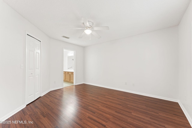 unfurnished bedroom with a closet, dark wood-style flooring, ceiling fan, and baseboards