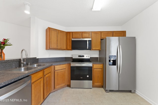 kitchen featuring dark countertops, brown cabinets, stainless steel appliances, and a sink