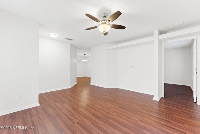 empty room featuring a ceiling fan, baseboards, visible vents, and wood finished floors