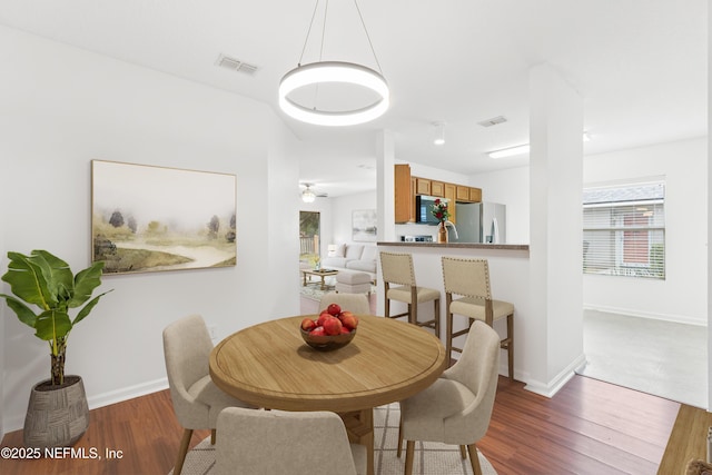 dining space featuring baseboards, visible vents, and wood finished floors