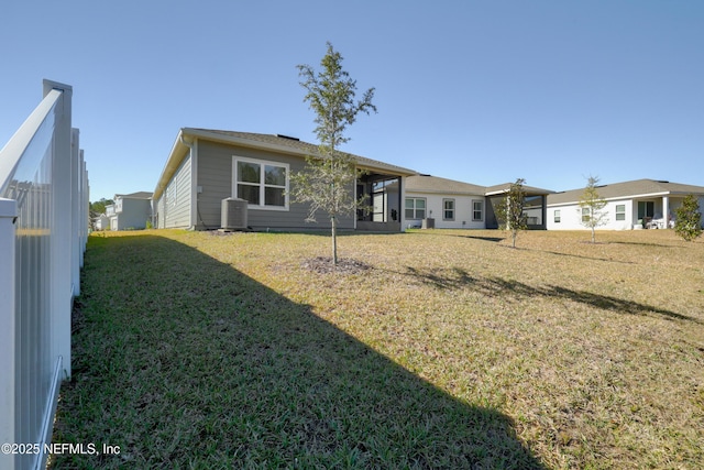 rear view of property featuring central air condition unit and a yard