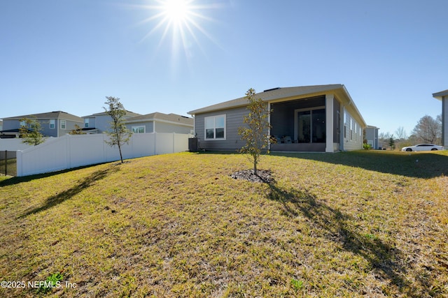 rear view of house with cooling unit, a yard, and a sunroom