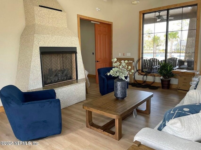 living room featuring ceiling fan, a fireplace, and hardwood / wood-style floors