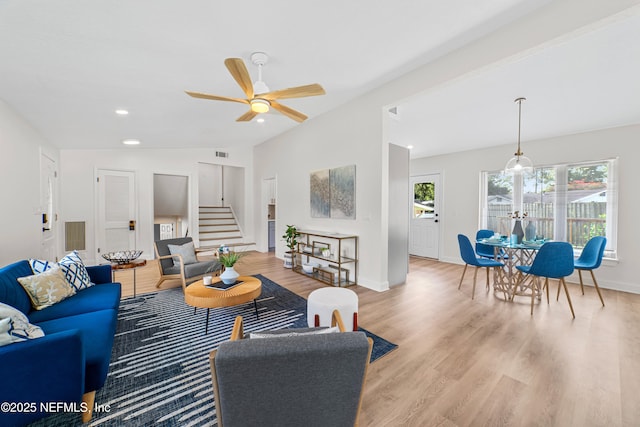 living room with ceiling fan, vaulted ceiling, and light hardwood / wood-style floors