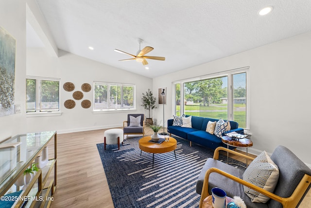 living room with vaulted ceiling, a textured ceiling, ceiling fan, and light hardwood / wood-style floors