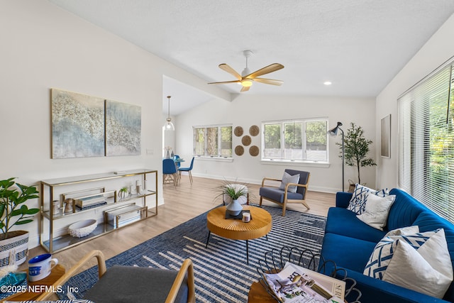 living room featuring vaulted ceiling with beams, a textured ceiling, light wood-type flooring, and ceiling fan