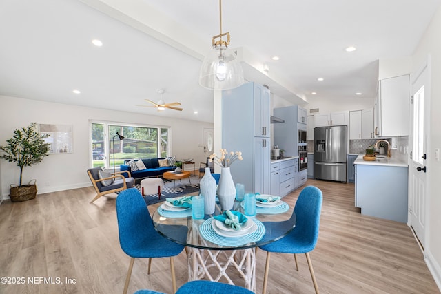 dining room featuring light hardwood / wood-style floors, ceiling fan, lofted ceiling with beams, and sink