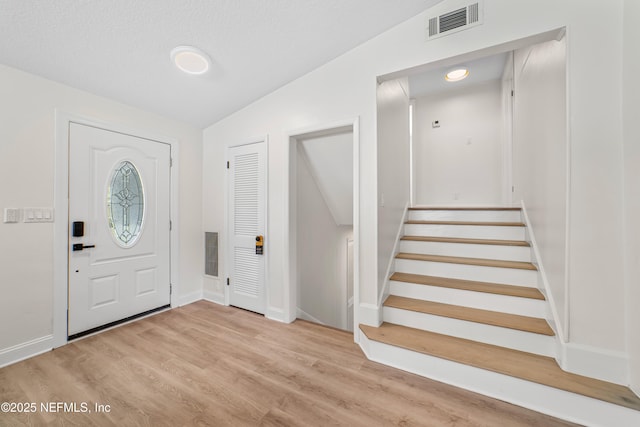 foyer entrance with light hardwood / wood-style flooring and vaulted ceiling