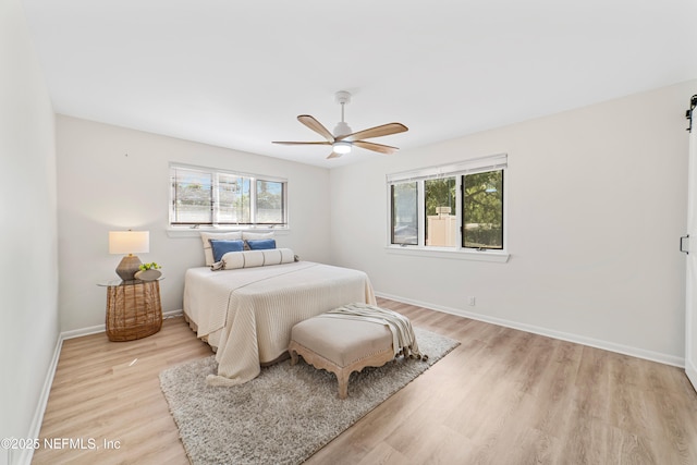 bedroom with ceiling fan, light wood-type flooring, and multiple windows