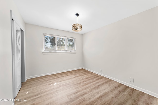 unfurnished bedroom featuring light wood-type flooring, an inviting chandelier, and a closet