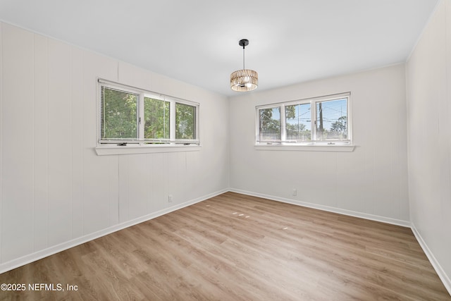 empty room featuring an inviting chandelier and light hardwood / wood-style floors