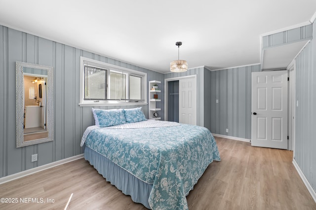 bedroom with a closet, an inviting chandelier, hardwood / wood-style flooring, and crown molding