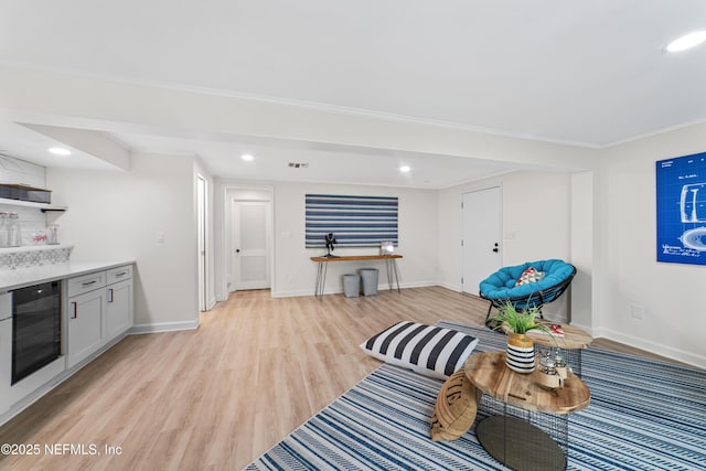 interior space featuring ornamental molding, light hardwood / wood-style flooring, and wine cooler