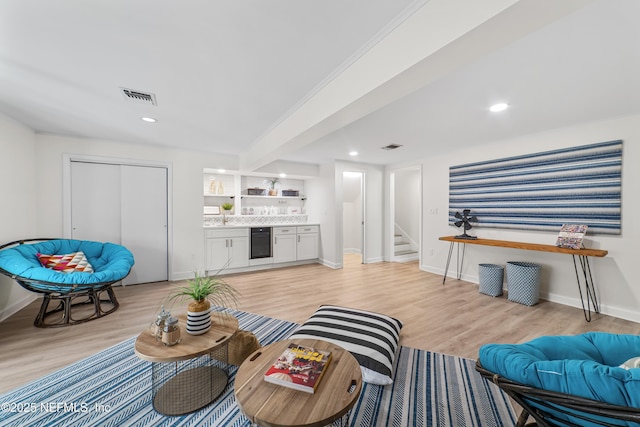 living room featuring beverage cooler, light wood-type flooring, built in shelves, and indoor bar