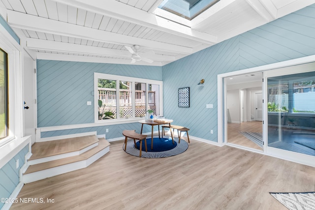 sunroom with a skylight, ceiling fan, and beamed ceiling