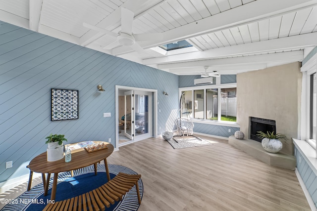 interior space featuring a skylight, wood-type flooring, ceiling fan, and beam ceiling