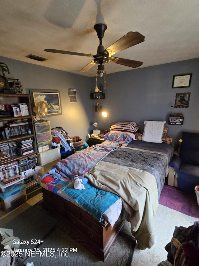 bedroom featuring carpet flooring, a textured ceiling, and ceiling fan