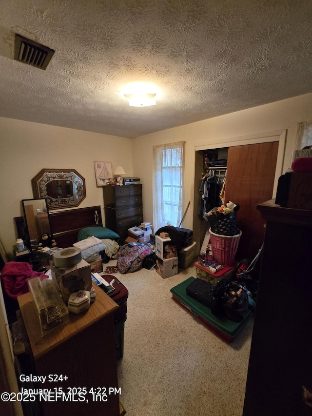 carpeted bedroom featuring a textured ceiling and a closet