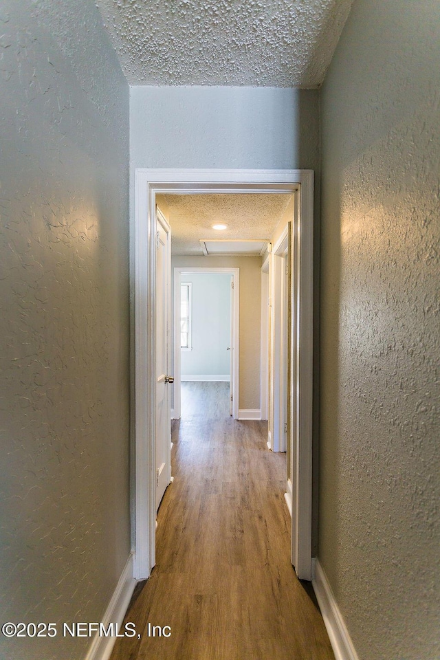 hallway with hardwood / wood-style flooring and a textured ceiling