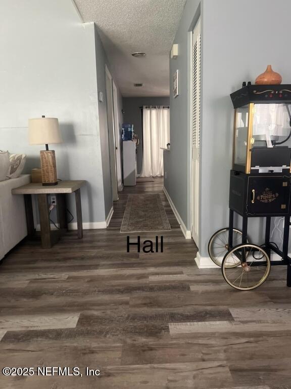 hall with a textured ceiling and dark hardwood / wood-style floors