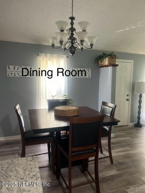 dining space featuring wood-type flooring, a chandelier, and a textured ceiling