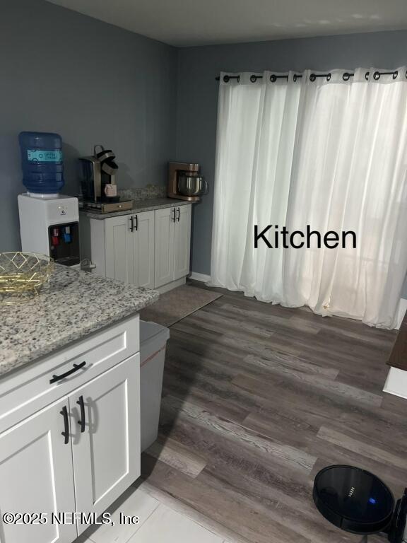 kitchen featuring light stone counters, hardwood / wood-style floors, and white cabinets