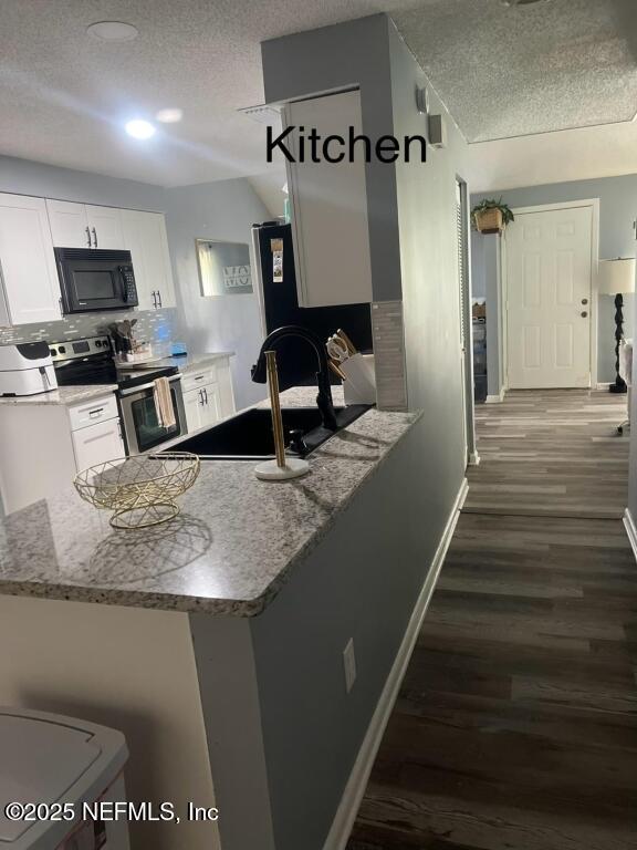 kitchen with a textured ceiling, white cabinetry, kitchen peninsula, and black appliances