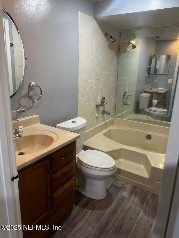 full bathroom featuring toilet, tiled shower / bath, hardwood / wood-style flooring, and vanity