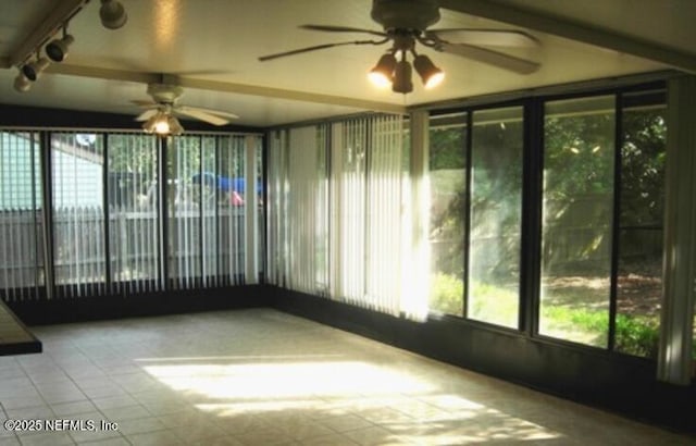 unfurnished sunroom featuring ceiling fan and a healthy amount of sunlight