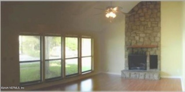 unfurnished living room featuring vaulted ceiling, ceiling fan, plenty of natural light, and a stone fireplace