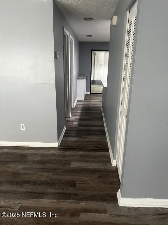 hall with a textured ceiling and dark hardwood / wood-style flooring