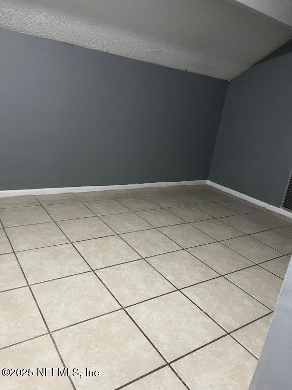 tiled spare room featuring a textured ceiling