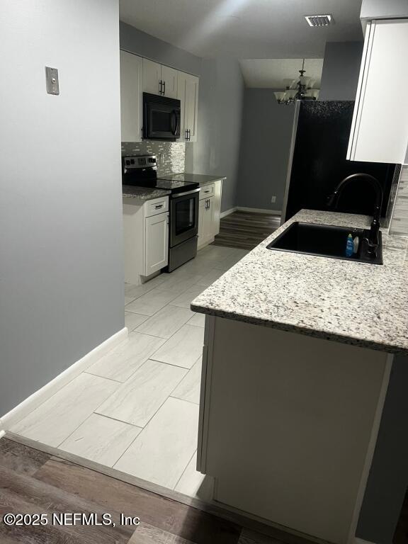 kitchen featuring white cabinets, stainless steel electric range oven, sink, and light stone counters