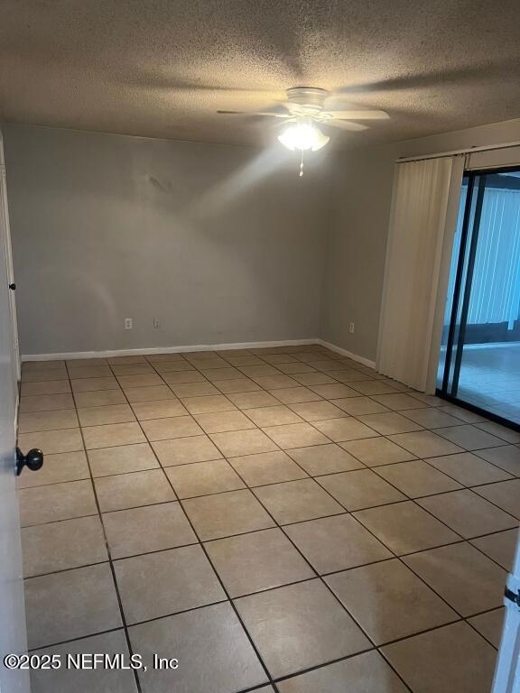 tiled spare room with a textured ceiling and ceiling fan