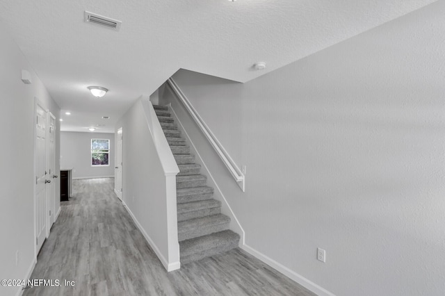 stairway with a textured ceiling and hardwood / wood-style flooring