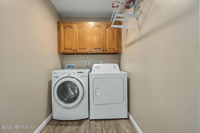 washroom featuring washer and dryer, cabinets, and light wood-type flooring