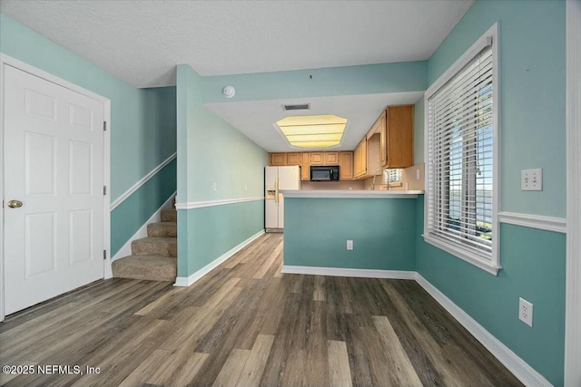 kitchen featuring dark wood-type flooring, kitchen peninsula, a textured ceiling, and white fridge with ice dispenser