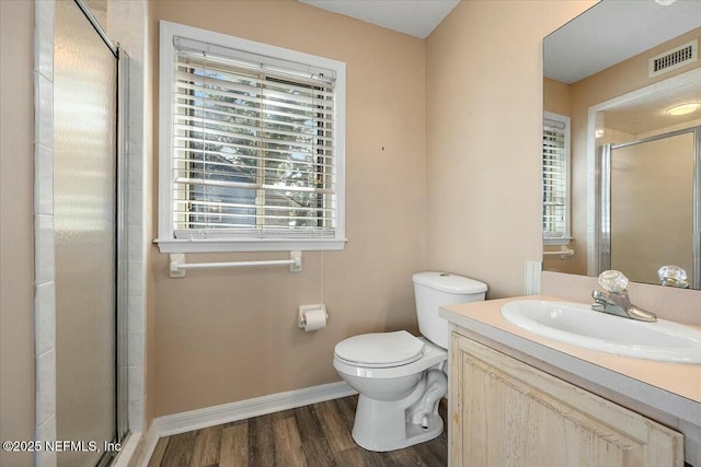 bathroom with vanity, hardwood / wood-style floors, a shower with shower door, and toilet