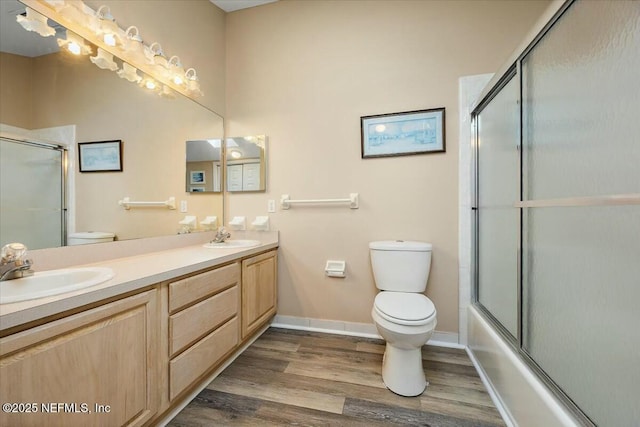 full bathroom with toilet, vanity, bath / shower combo with glass door, and hardwood / wood-style floors