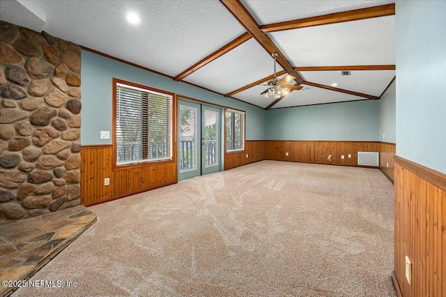 unfurnished living room with crown molding, ceiling fan, lofted ceiling with beams, a textured ceiling, and light colored carpet