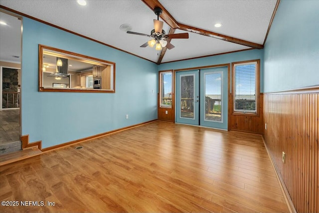 empty room featuring ornamental molding, lofted ceiling with beams, french doors, and a textured ceiling