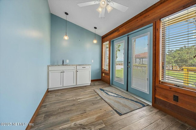 interior space featuring lofted ceiling, wood-type flooring, french doors, and a healthy amount of sunlight