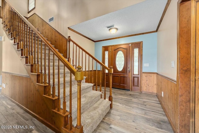 entryway featuring ornamental molding, a textured ceiling, and light hardwood / wood-style flooring