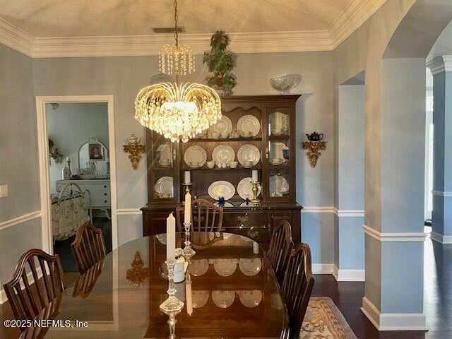 dining area with decorative columns, ornamental molding, dark hardwood / wood-style floors, and a notable chandelier