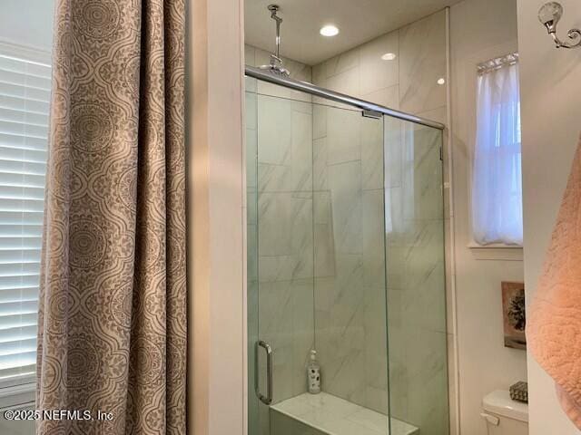 bathroom with a shower with shower door and toilet