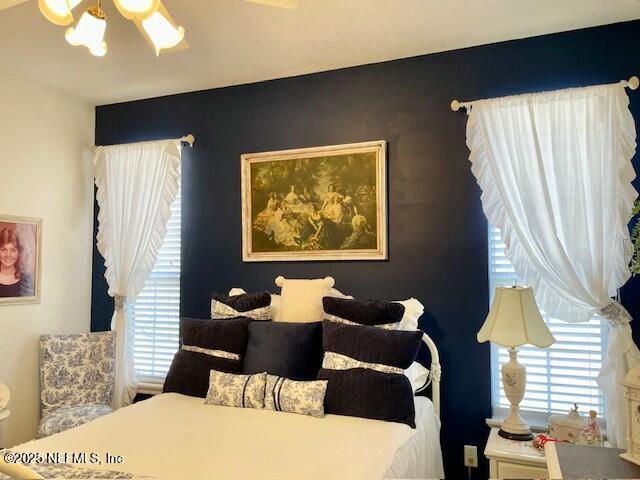 bedroom featuring ceiling fan with notable chandelier