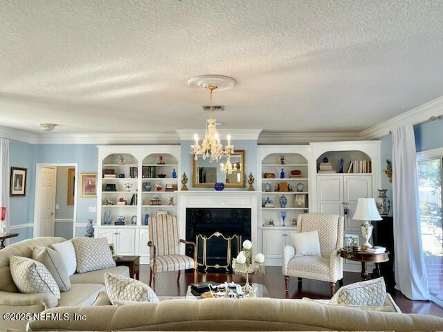 living room with a textured ceiling, an inviting chandelier, ornamental molding, and a fireplace